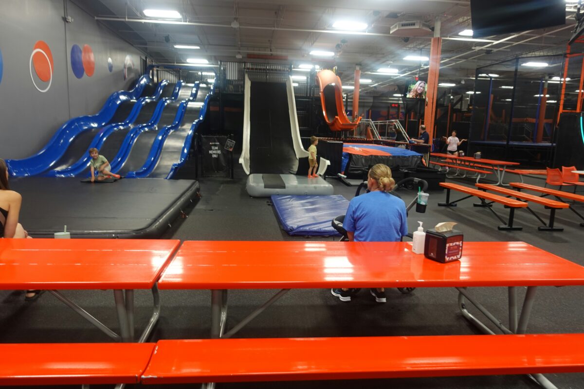 Indoor trampoline park with various activity stations. 