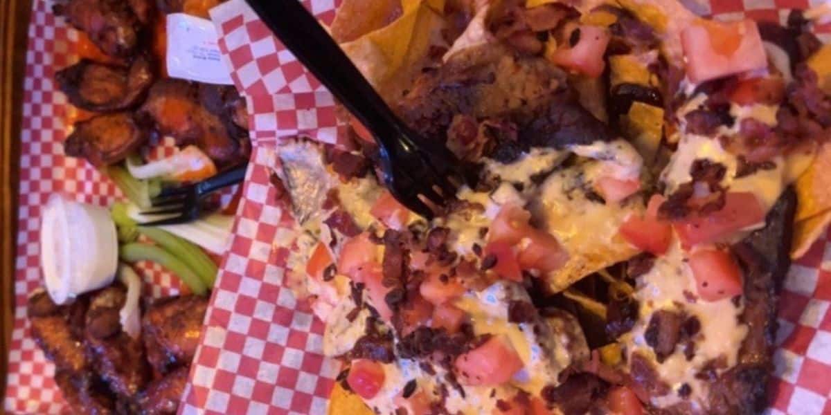 Loaded pull pork nachos topped with pico and cheese and a side of wings from Camel City Barbecue